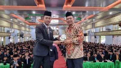 Ust. Agus Maulana menerima kenang-kenangan.